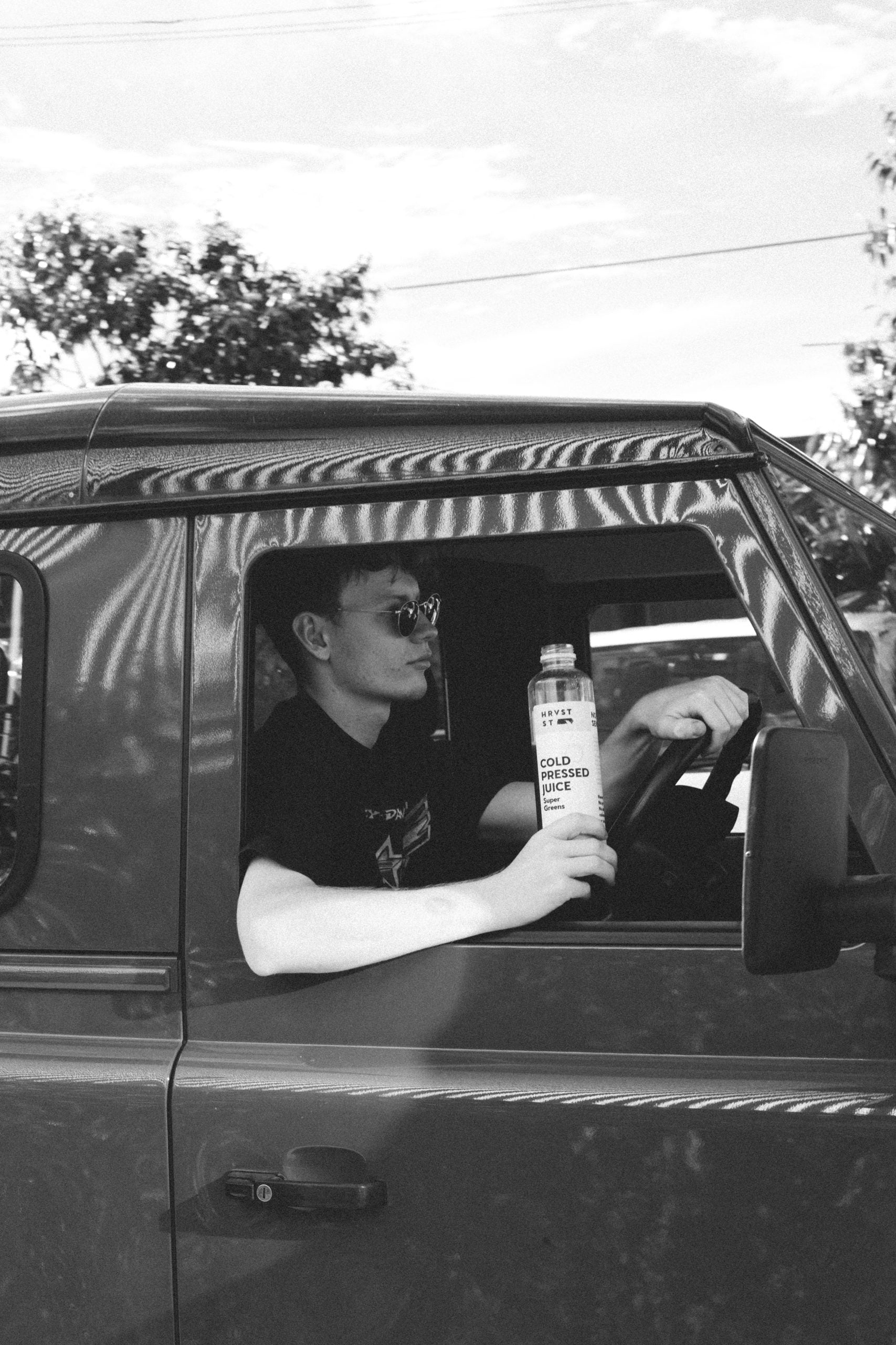 Man in a vehicle showing Hrvst St juice while driving